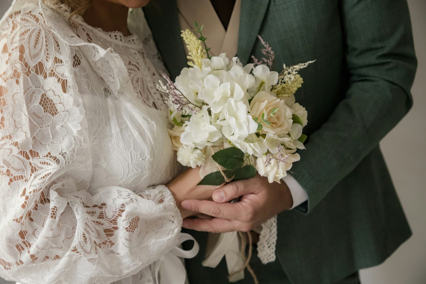 A couple standing together outdoors with a bouquet